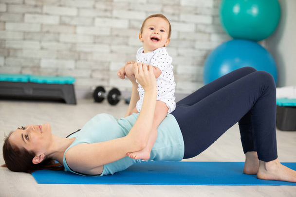jovem mãe faz exercícios de aptidão física junto com seu bebê - Foto, Imagem