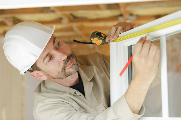 male builder measuring a window - Φωτογραφία, εικόνα
