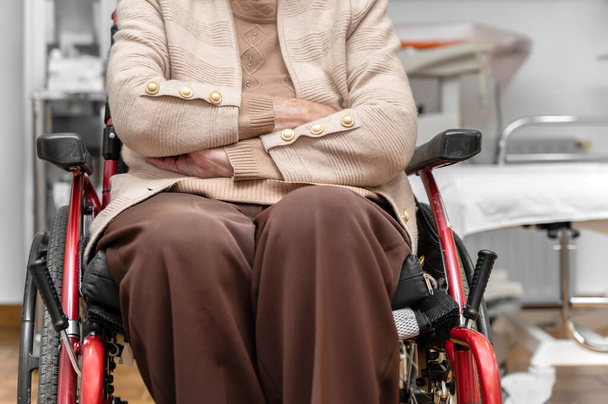 Starsza kobieta na wózku inwalidzkim w klinice rehabilitacyjnej lub gabinecie lekarskim, nierozpoznana starsza kobieta. Wysokiej jakości zdjęcie. Wysokiej jakości zdjęcie - Zdjęcie, obraz