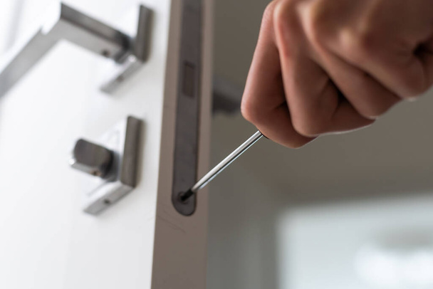 Schlosser Schreiner fixieren Knopf an weißer Tür mit Schraubenzieher für Reparatur zu Hause. Hochwertiges Foto - Foto, Bild