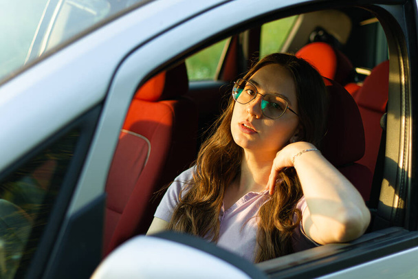 woman sitting in car.road trip.woman driver.driving lessons.problems on the road.portrait in car.pensive woman.serious woman in the car.woman with car.upset girl.portrait.girl dreams.deep look.motional girl in the auto.woman thinking and dreaming - Valokuva, kuva