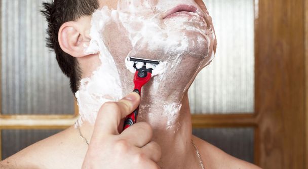 El proceso de afeitar la cara con una navaja de afeitar
  - Foto, imagen