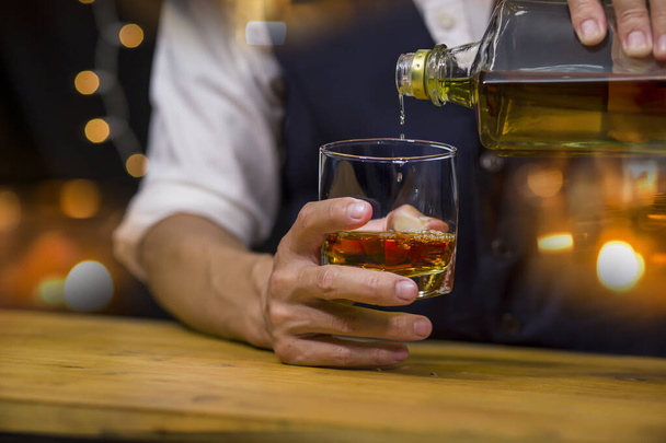 Бармен подает виски, на деревянном баре, - Фото, изображение