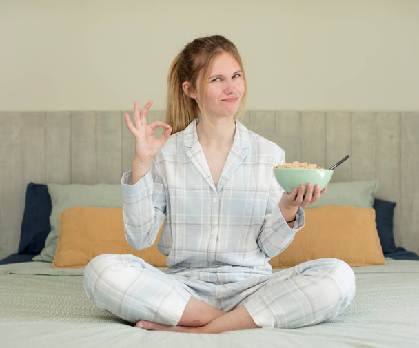 young pretty woman feeling happy, showing approval with okay gesture. breakfast bowl concept - 写真・画像
