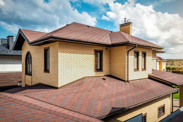 Modern roof of the house with new brown roof shingles under cloudy sky - Photo, Image