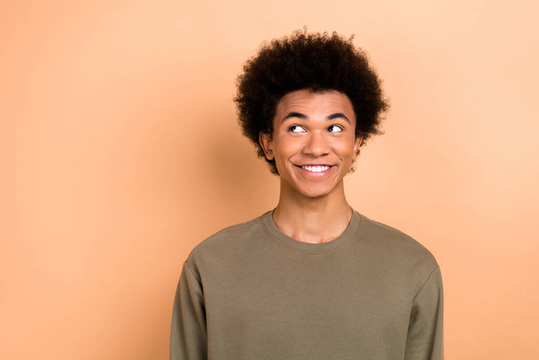 Photo of satisfied curious optimistic guy with afro hairstyle dressed khaki shirt look empty space isolated on beige color background. - Foto, immagini