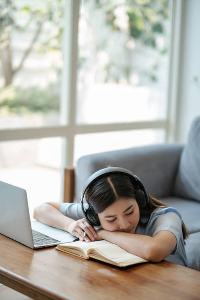 Junge Frau dösen am Laptop während eines langweiligen Webinars oder Vortrags, Konzept der Online-Arbeit oder des Studiums. Hochwertiges Foto - Foto, Bild