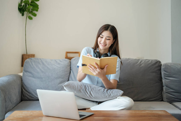 Красива азіатська жінка онлайн вчиться з ноутбуком у вітальні. Високоякісна фотографія
 - Фото, зображення