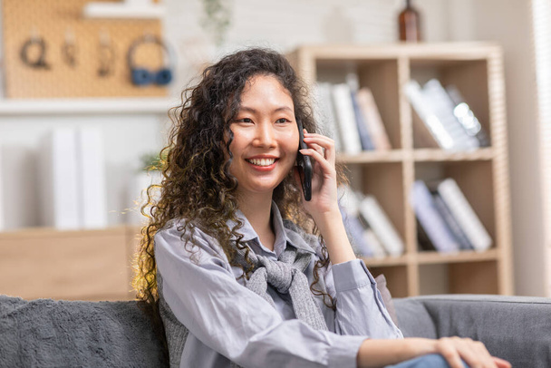 Asian young woman answer the phone and talking with positive and happiness emotional.Attractive female talkin in smartphone smile and cheeful with good news and good moment at home - Fotografie, Obrázek