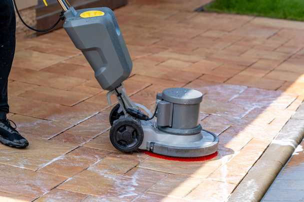 machine reinigen betonnen bestrating in de voorkant van het huis met een borstel. Hoge kwaliteit foto - Foto, afbeelding