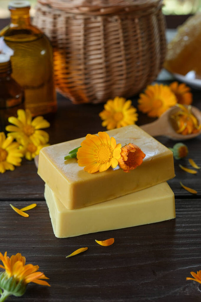 Natural handmade soap with calendula (pot marigold), oil essential and honeycomb on rustic wooden background. Healthy skin care. SPA concept. Side view. - Photo, image