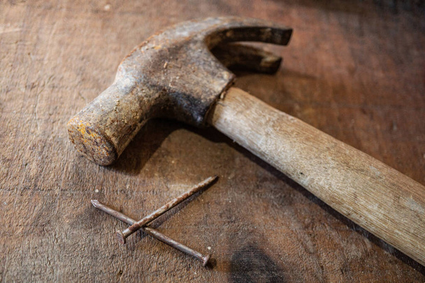 Hammer and rusty  nail on top of rustic wooden table - 写真・画像