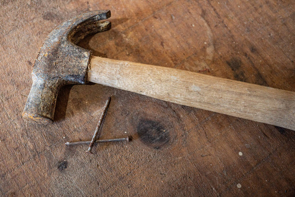 Hammer and rusty  nail on top of rustic wooden table - Foto, Imagem
