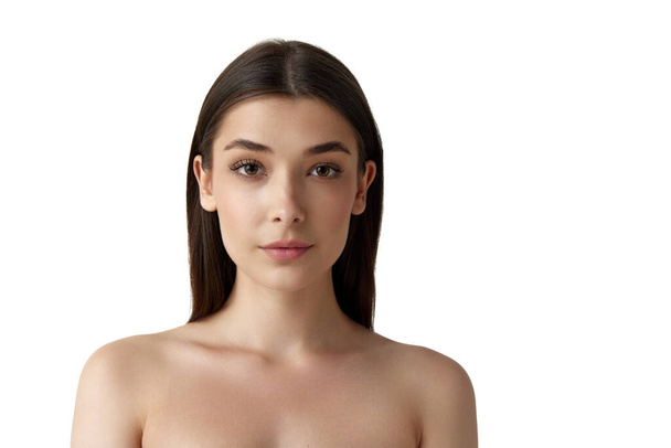 Tender, beautiful young woman with bare shoulders, well-kept, smooth, healthy skin looking at camera over white studio background. Concept of female beauty, body and skincare, cosmetology, health, ad - Fotografie, Obrázek