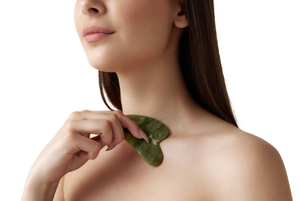 Cropped image of woman with well-kept healthy skin taking care after body with cosmetological massage tool over white background. Concept of natural female beauty, body and skincare, cosmetology, ad - Φωτογραφία, εικόνα
