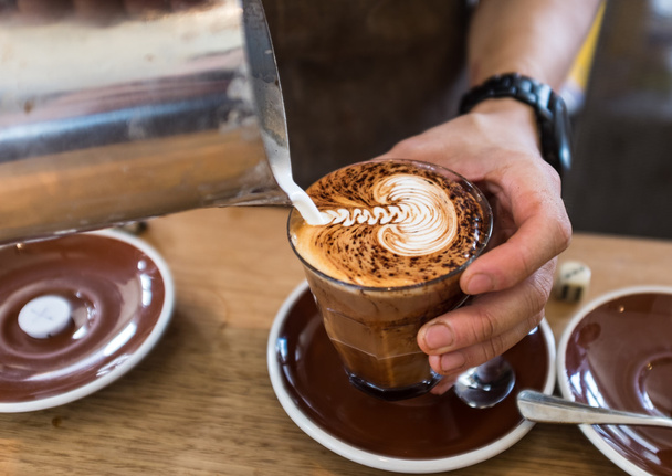 Barista derramando padrão de folha em um café cappuccino
 - Foto, Imagem