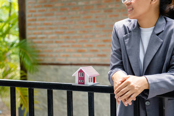 domácí model stojí na plotě s realitním makléřem před domácí zdí nebo prodej prezentující pojištění domácnosti. - Fotografie, Obrázek