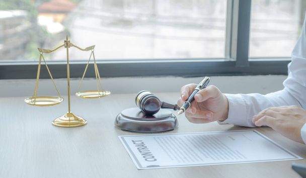 Lawyer hand holding pen and providing legal consult business dispute service at the office with justice scale and gavel hammer. - Foto, Bild