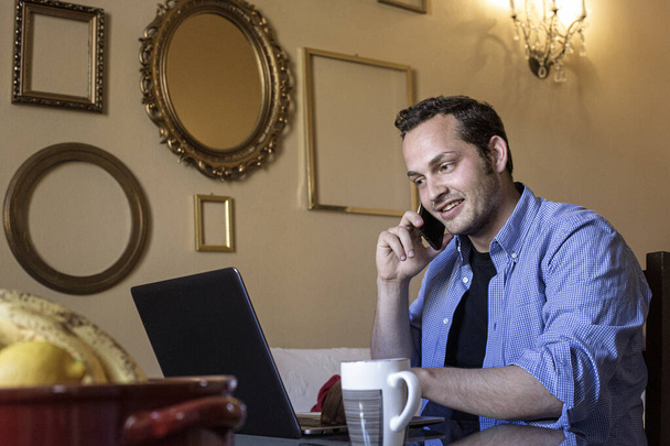 joven hombre de negocios hablando por teléfono móvil mientras está sentado en la cafetería - Foto, Imagen