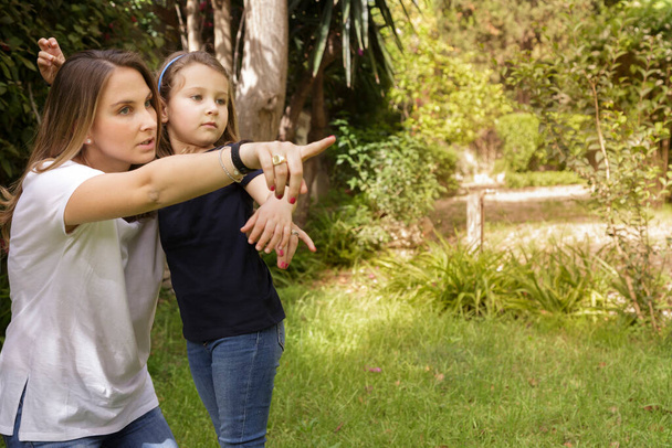 mother with daughter pointing finger in park - Foto, Imagen