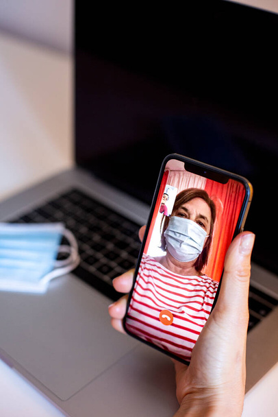 férfi birtoklás video hívás a nő orvosi maszk segítségével smartphone  - Fotó, kép