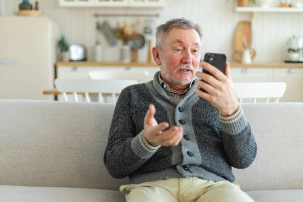 Boldog középkorú öregember beszél videohíváson a barátaival. Nevető, érett, idős nagyapa jól érzi magát felnőtt gyerekekkel online. Idősebb generációs modern technológia használata - Fotó, kép