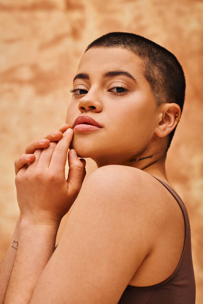 body positivity and confidence, curvy and young woman posing on mottled beige background, short haired, looking at camera, self-acceptance, generation z, tattooed, different shapes, portrait  - 写真・画像