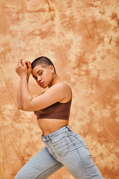 denim fashion, gen z, young curvy woman with tattoo posing on mottled beige background, different shapes, body positivity movement, self-esteem, confidence, short haired model, youth culture  - Foto, imagen