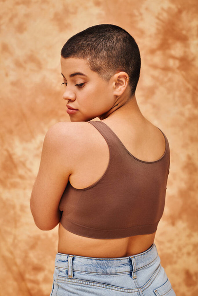 natural beauty, self-esteem, young woman with short hair posing on mottled beige background, individuality, modern generation z, beauty and confidence, body positivity, curvy model  - Fotó, kép