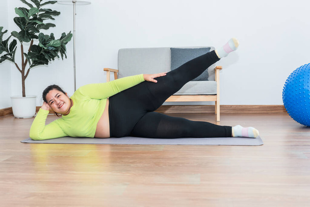 Азиатская толстая женщина делает упражнения дома, растягивая мышцы ног, людям здравоохранения и физических упражнений для концепции потери веса. - Фото, изображение