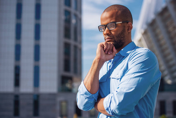 Nachdenklicher junger Geschäftsmann mit Brille denkt im Freien - Foto, Bild