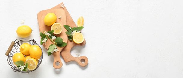 Cutting boards and basket with fresh lemons and blooming branches on white background with space for text - Zdjęcie, obraz