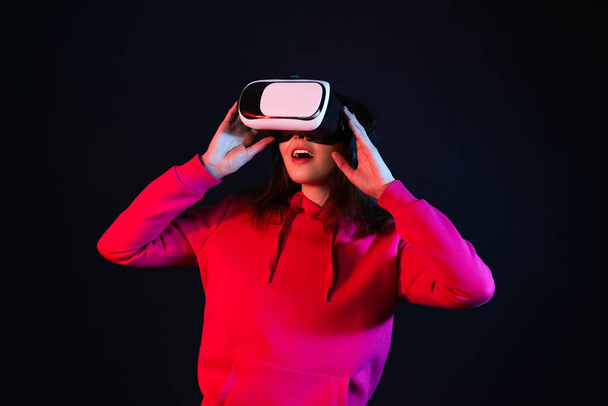Pretty young woman in VR glasses on black background - Foto, Imagem