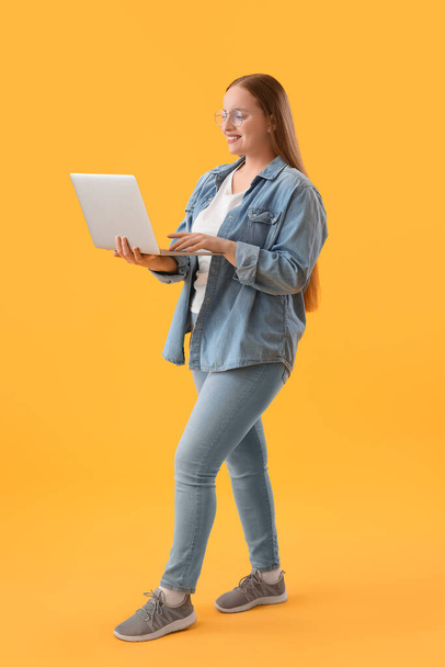 Female programmer working with laptop on yellow background - 写真・画像