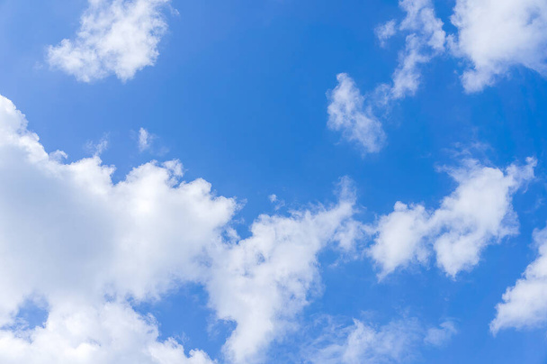 Hipnotyzująca fotografia ukazująca promienne błękitne niebo z błyszczącymi, bawełnianymi chmurami - Zdjęcie, obraz