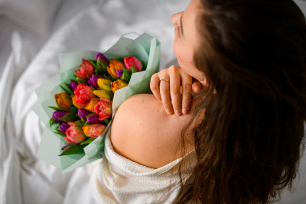 Young bride in hotel room hold bouquet of colorful tulips, top view . Celebrate bachelorettes party. - Fotó, kép