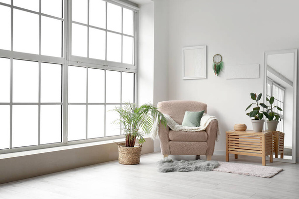 Intérieur du salon moderne avec fauteuil, plantes et attrape-rêves suspendus au mur léger - Photo, image