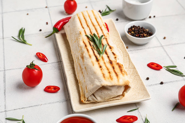 Plate of tasty shawarma with rosemary and chilli on white tile table - Foto, afbeelding