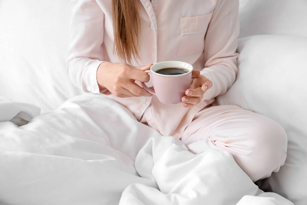 Γυναίκα κρατώντας φλιτζάνι νόστιμο καφέ στο κρεβάτι - Φωτογραφία, εικόνα