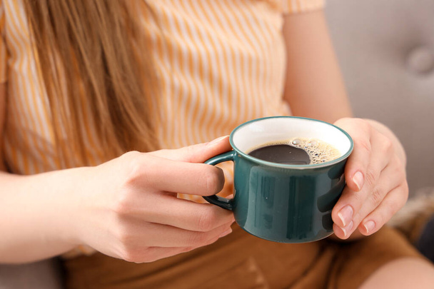 Mulher sentada na poltrona aconchegante e segurando xícara de café delicioso - Foto, Imagem