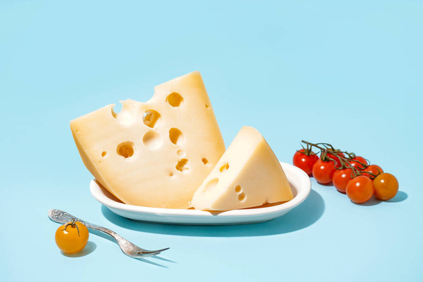 Mavi arka planda İsviçre peyniri ve domatesli tabak. - Fotoğraf, Görsel