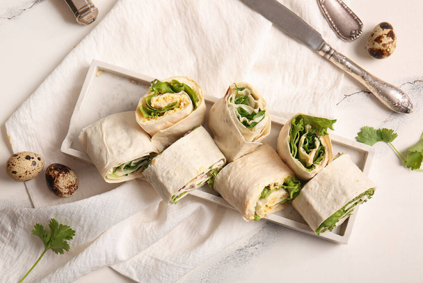 Plate of tasty lavash rolls with egg, onion and greens on white marble background - Foto, Bild