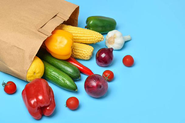 Paper bag with fresh vegetables on blue background - Fotó, kép