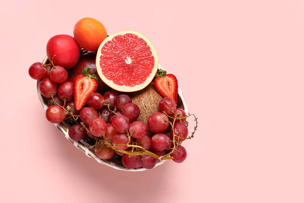 Cuenco de mimbre con diferentes frutas frescas sobre fondo rosa - Foto, Imagen