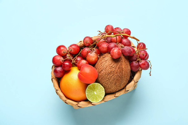 Плетеная корзина с различными свежими фруктами на голубом фоне - Фото, изображение