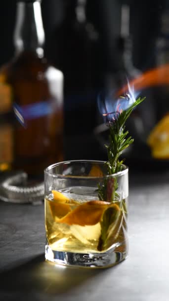 Cóctel Old Fashioned Negroni. La astringencia del whisky está nivelada por el azúcar, y la tintura de hierbas y el romero ahumado agregan sabor y notas originales. Servido con hielo y naranja - Metraje, vídeo