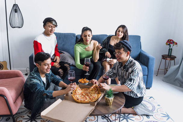 Grupo de amigos latinos LGBT comiendo pizza, bebidas y divirtiéndose en casa en México, comunidad hispana homosexual e lgbtq en América Latina en fiesta - Foto, imagen