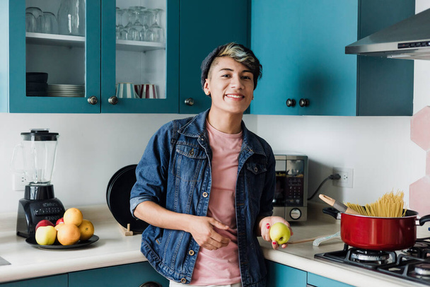 メキシコの家庭で台所で調理する若いラテン系の同性愛者、ラテンアメリカで料理を作るヒスパニック系のLGBTの人々 - 写真・画像