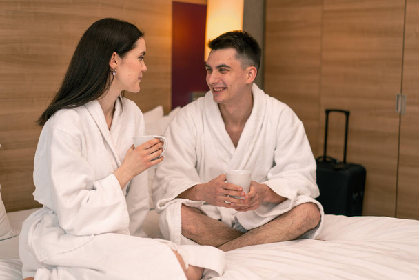 mladý pár na líbánky v hotelovém pokoji se snídaní pokoj pití kávy šťastní milenci cestovní koncept - Fotografie, Obrázek