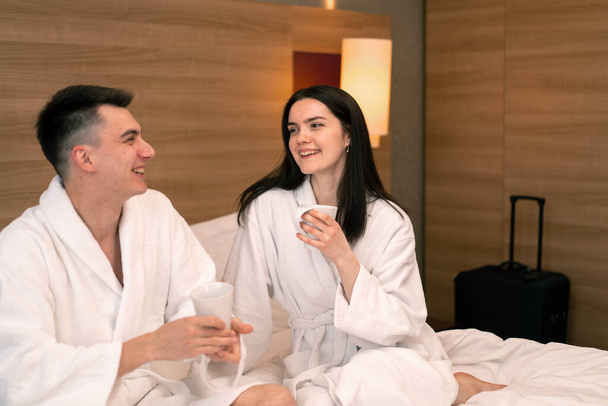 jong paar op huwelijksreis in hotelkamer ontbijtruimte drinken koffie gelukkige liefhebbers reizen concept - Foto, afbeelding